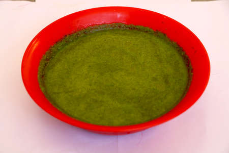 Green chutney(sauce) in red bowl with white backgroundの写真素材