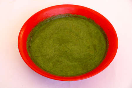 Green chutney(sauce) in red bowl with white backgroundの写真素材
