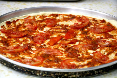 view of preparation of pizza in kitchen with pizza souse and tomatoの写真素材