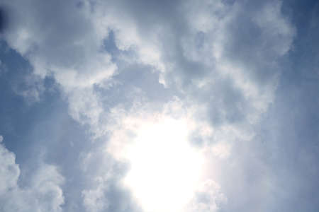 Dramatic sky bright sun behind cloud in blue skyの写真素材
