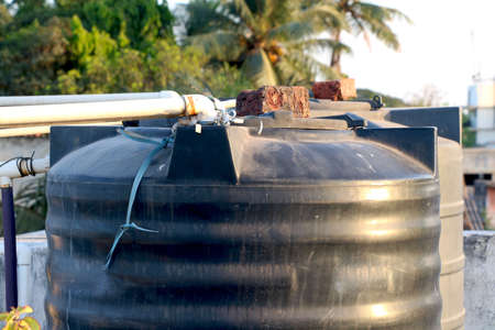 Big water tank with brick on container cover on top of roof topの写真素材