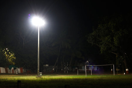 halogen lamp glowing on pole in empty sports ground at nightの写真素材