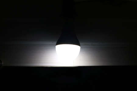 view of glowing bulb in dark room above mirrorの写真素材