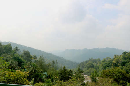 Areal view of mountain with green trees and grass on it with blue skyの写真素材