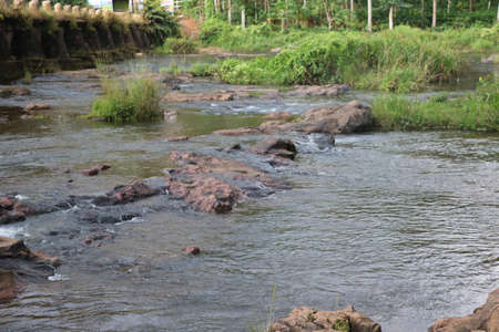 Flowing water from stone in river with bridge at backgroundの写真素材