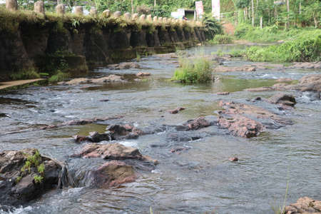 Flowing water from stone in river with bridge at backgroundの写真素材