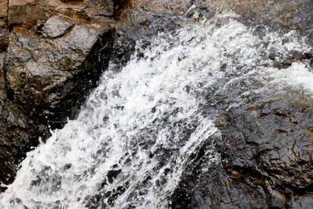 water flowing from rock near waterfallの写真素材