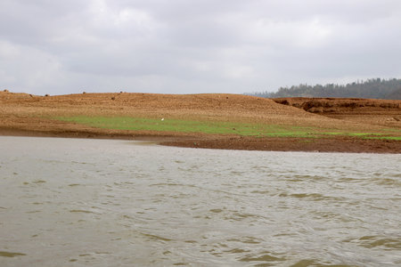 landscape view of river bank with dry land and hill on background from boatの写真素材
