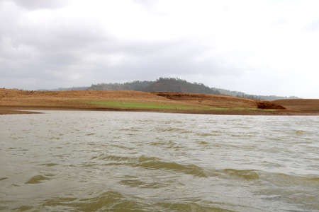 landscape view of river bank with dry land and hill on background from boatの写真素材