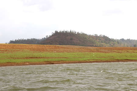 landscape view of river bank with dry land and hill on background from boatの写真素材