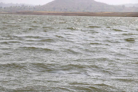 landscape view of river bank with dry land and hill on background from boatの写真素材