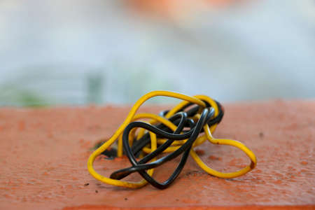 portrait view of black and yellow wire are messed which coming out from holeの写真素材