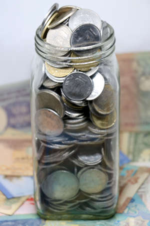 glass jar full of coins on isolated backgroundの写真素材