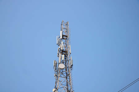 Telecommunication towers with TV antennas and satellite dish on clear blue skyの写真素材