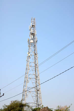 Telecommunication towers with TV antennas and satellite dish on clear blue skyの写真素材