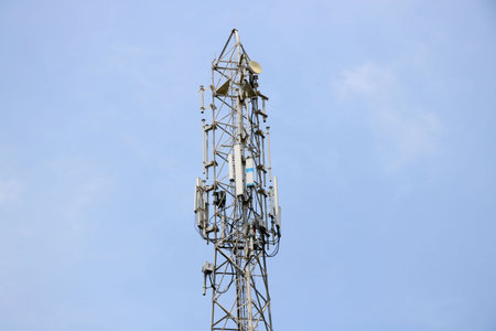 Telecommunication towers with TV antennas and satellite dish on clear blue skyの写真素材
