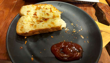 cheese garlic bread slice served with tomato sauce in black plate able in restaurantの写真素材
