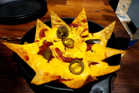 nachos served with yellow cheese and tomato sauce , jalapeno on topの写真素材