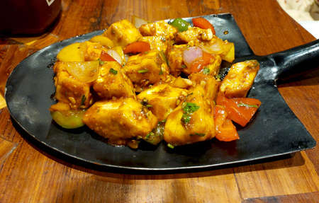 paneer 65 served in digging scoop on wooden table in restaurantの写真素材