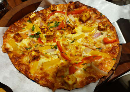Think crust pizza with paneer, peeper, onion served in restaurantの写真素材
