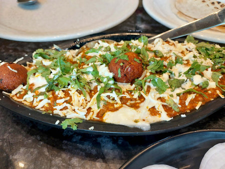 Malai Kofta Curry in black bowl. Malai Kofta is indian cuisine dish with potato and paneer cheese deep fried balls in onion tomato gravy with spices. Indian Food.の写真素材