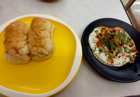 Egg half fry garnish with coriander leaves green onion and spices served in plate with bunの写真素材