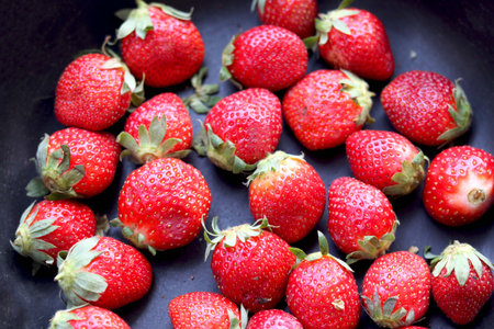 Red ripe strawberries background. Close up, top view. in black panの写真素材