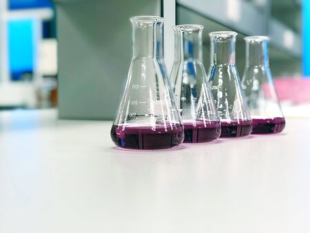 The Erlenmeyer or Conical flask on bench laboratory, with purple solvent forming reaction between boric acid and ammonia solution analysis concentration in wastewater sample. Selective focus.の写真素材