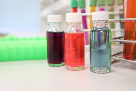 Vial White cap with colorful solvent solutions on laboratory with colorful culture cell tubes cover...