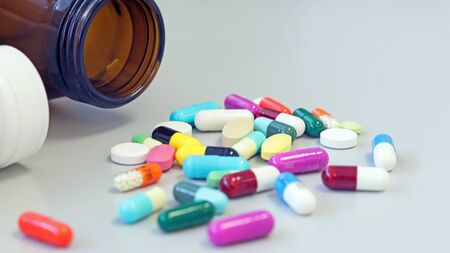 Colorful tablets, pills and capsules medicine from glass and white bottle using for treatment and cure disease or sickness. Drug prescription using for medication in medical clinic, pharmacy concept.の写真素材