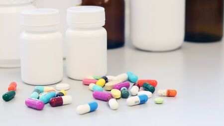 White and Brown glass medicine bottles with colorful tablets, pills, capsules drugs using for treatment and cure the disease or sickness. Drug prescription for medication isolate in white background.の写真素材