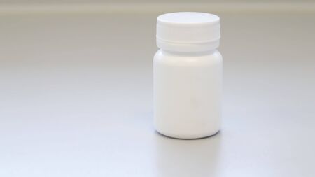 Mock up white medicine bottle or jar with cap template isolated in white medical room background, medicine packaging for medication pills, tablets, capsules drug pharmaceutical or Supplement vitamin.の写真素材