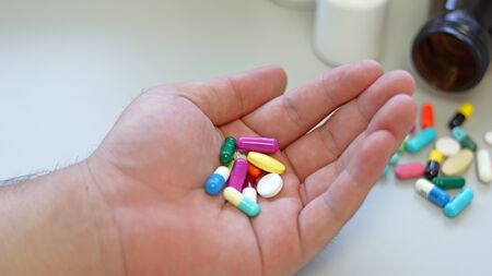 Obesity patient take medicine colorful tablets, pills and capsules in hand for treatment and cure disease or sickness. Drug prescription use for medication in medical clinic, pharmacy service concept.の写真素材