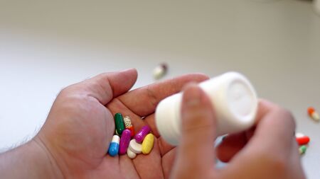 Obesity patient take medicine colorful tablets, pills and capsules in hand for treatment and cure disease or sickness. Drug prescription use for medication in medical clinic, pharmacy service concept.の写真素材