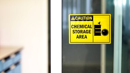 Black-yellow Chemical storage area Hazard Sign and symbol on the glass door, Caution for warning dangerous space in laboratory room. selective focus on tag, blurred background Safety first concept.の写真素材
