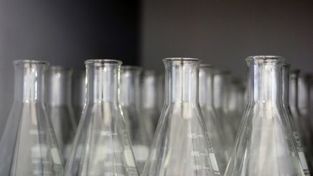 Transparent Erlenmeyer flasks or conical flasks on shelf in science laboratory, use for measuring...