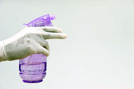 Hand wears latex gloves using spray bottle with antibacterial soap sanitizer alcohol, ethanol 70%...