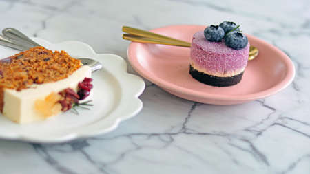 Blueberry cheese pie cake and whipped cream on pink plate with golden spoon, eat with carrot cheese cake good for eating with coffee, yummy and tasty relaxing day, isolated in white granite table.の写真素材