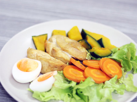 Clean meal keto food with chicken, eggs seasoning with sesame sauce healthy for diet dining, eat with vegetables, carrot, beans and pumpkin. Put on the white plate isolated in greyの写真素材