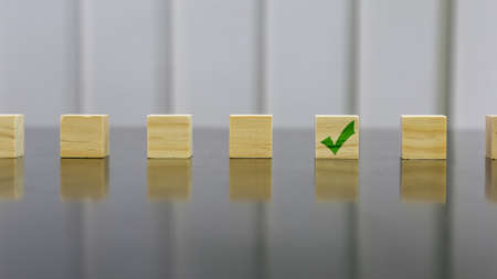 Right green icon on wooden cube on black gloss wooden table. Background concept for chose and decide. Selected focus.の写真素材