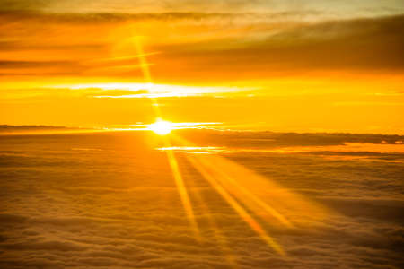 Sunset seen from airplane above the cloudsの写真素材