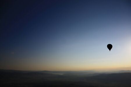 Flying silhouette hot air balloon over the landscape viewの写真素材