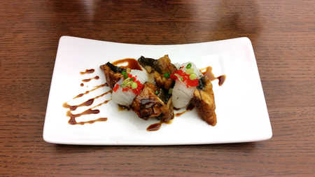 Engawa Unagi Nigiri Sushi Dish decorated with sweet source in white ceramic dish on wooden tableの写真素材