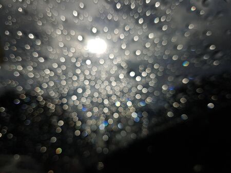 Sunlight bokeh in cloudy day. Blurry raindrop on the window.の写真素材