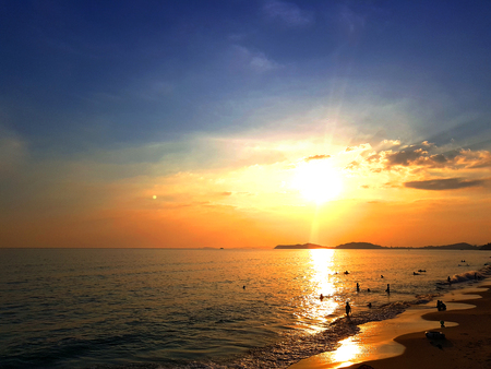 Sunset at the beach, golden sky, beautiful scene. people enjoy the beach in silhouetteの写真素材