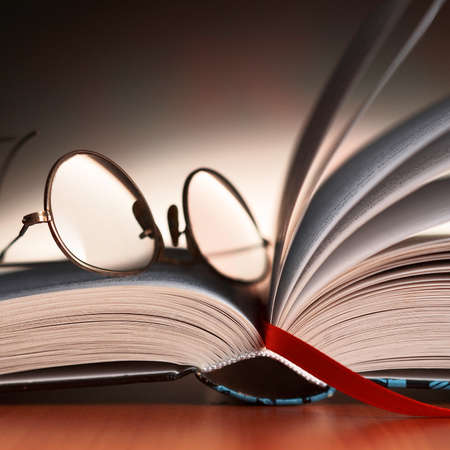 Close up detail of reading glasses on the book