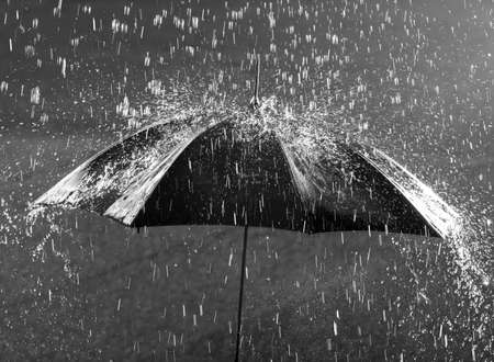 Black and white photo of umbrella in heavy rainの写真素材