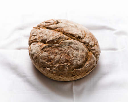 Rye loaf of bread still life on white decorated table