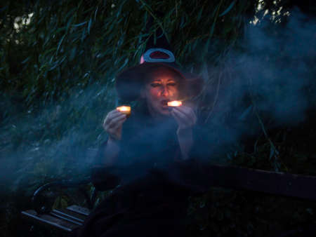 Scary witch with candles in haunted forestの写真素材