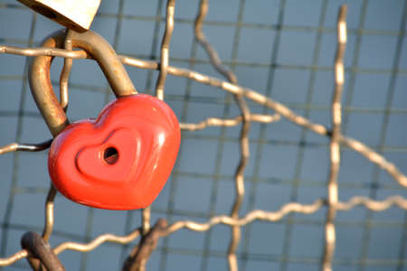 Padlock with heart sign hung on the bridge of loveの写真素材
